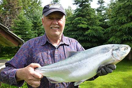 Dennis holding shiny red salmon.
